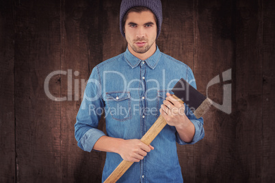 Composite image of serious hipster wearing knitted hat holding axe