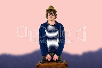 Composite image of serious hipster holding a suitcase