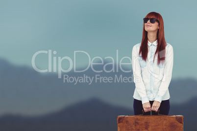 Composite image of smiling hipster woman holding suitcase