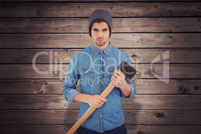 Composite image of serious hipster wearing knitted hat holding a