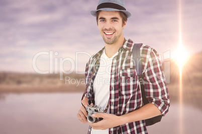 Composite image of portrait of man smiling while holding camera