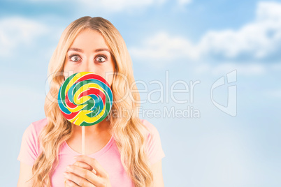 Composite image of a beautiful woman holding a giant lollipop