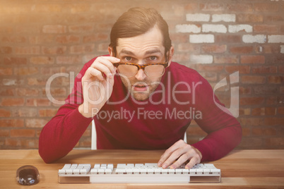 Composite image of surprised creative businessman working at des