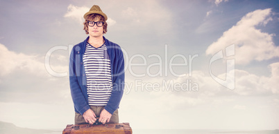 Composite image of serious hipster holding a suitcase