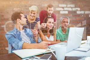 Composite image of creative business team using laptop in meetin