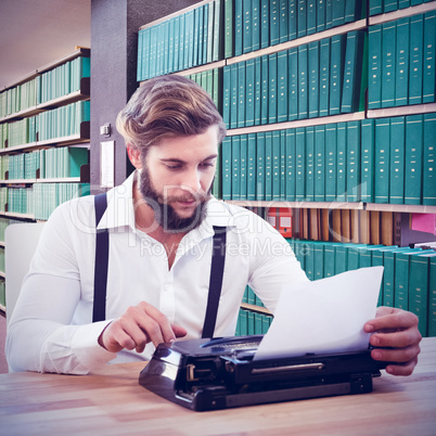 Composite image of hipster using typewriter at desk in office