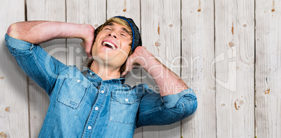 Composite image of cheerful hipster listening to music