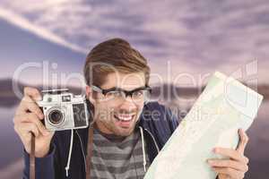 Composite image of portrait of happy man holding map and camera