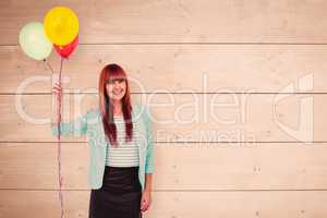 Composite image of smiling hipster woman holding balloons