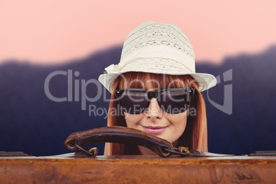 Composite image of smiling hipster woman behind a suitcase