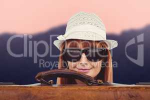 Composite image of smiling hipster woman behind a suitcase