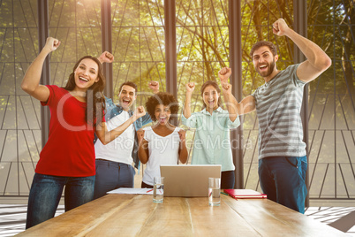 Composite image of happy business team with fists in the air