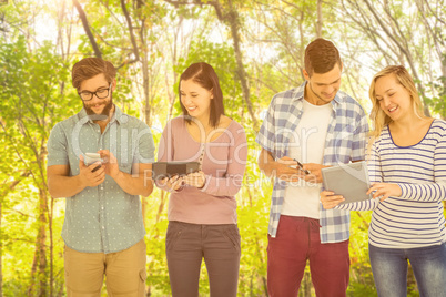 Composite image of smiling business people using electronic gadg