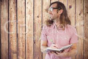Composite image of happy hipster holding book and pen