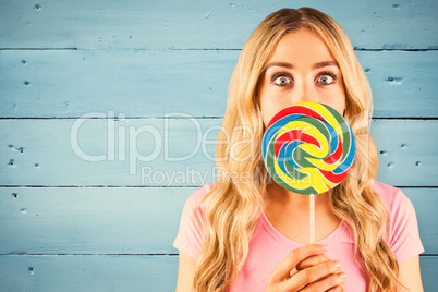 Composite image of a beautiful woman holding a giant lollipop