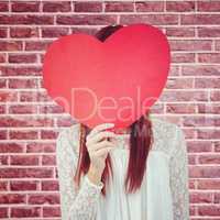 Composite image of smiling hipster woman behind a big red heart