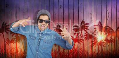 Composite image of happy hipster showing rock and roll hand sign