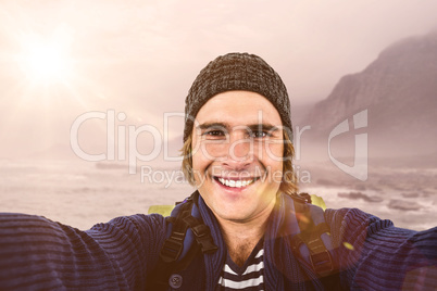 Composite image of smiling backpacker hipster holding the camera