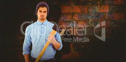 Composite image of portrait of serious hipster holding axe