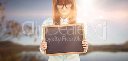 Composite image of smiling hipster woman holding blackboard