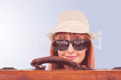 Composite image of smiling hipster woman behind a suitcase