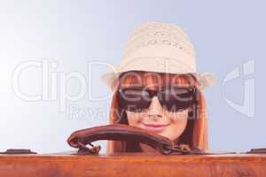 Composite image of smiling hipster woman behind a suitcase