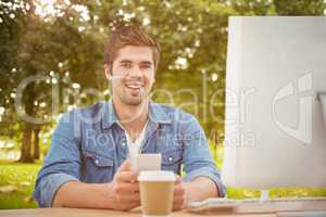 Composite image of happy businessman holding mobile phone at des
