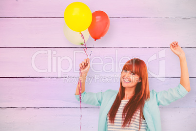 Composite image of smiling hipster woman holding balloons