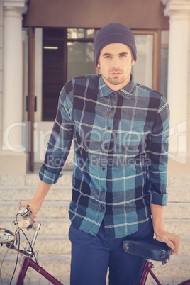 Composite image of portrait of hipster standing with bicycle