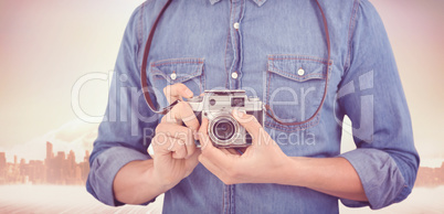 Composite image of mid section of man adjusting camera lens