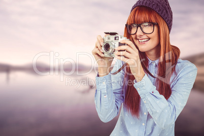 Smiling hipster woman taking pictures with a retro camera