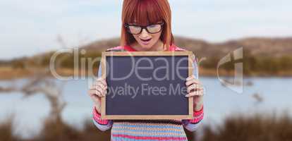 Composite image of smiling hipster woman holding blackboard