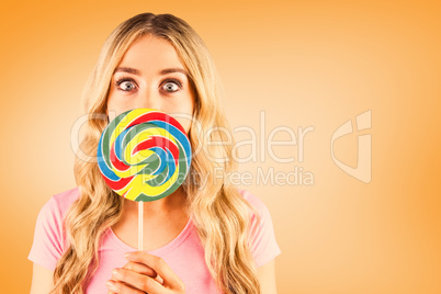 Composite image of a beautiful woman holding a giant lollipop