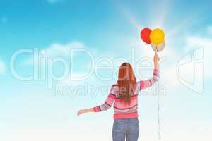 Composite image of rear view of hipster woman holding balloons