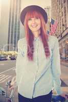 Composite image of smiling hipster woman leaning on a bike