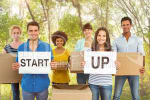 Composite image of creative business team holding cardboard writ