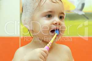 child in the bathroom brushing her teeth with a toothbrush