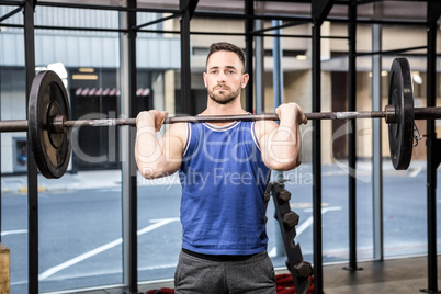 Muscular man lifting barbell on bench