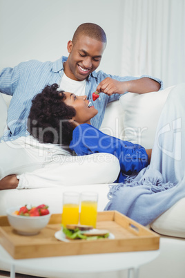 Handsome man feeding his girlfriend with strawberry