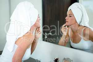 woman wearing a  hair towel inspecting her skin