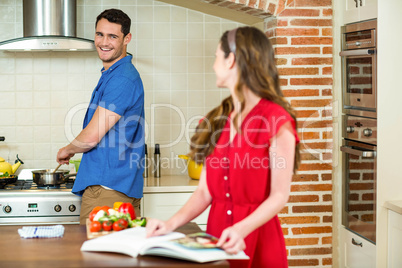 Man and woman talking together while working in kitchen