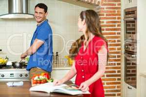Man and woman talking together while working in kitchen