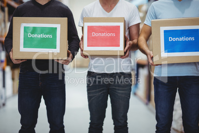 Volunteers smiling at camera holding donations boxes