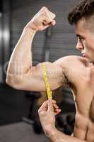 Shirtless man measuring biceps