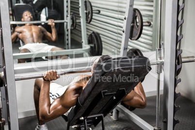 Shirtless man lifting barbell on bench