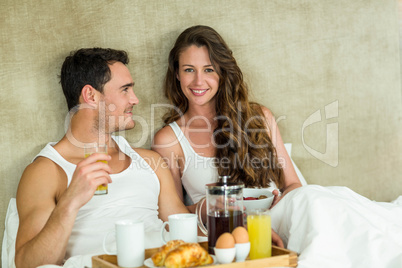 Young couple having breakfast on bed