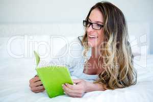 smiling woman lying on her bed reading