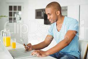 Smiling man using laptop and smartphone