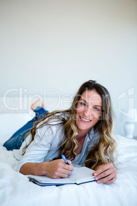 woman lying on her bed writing in a book