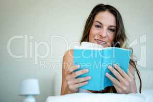 smiling woman in bed reading a book